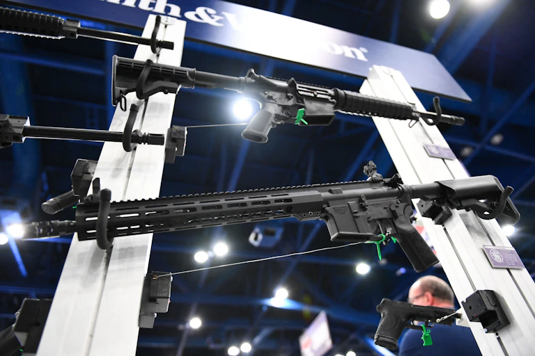 A rack of rifles are seeon underneath a 'Smith & Wesson' sign.