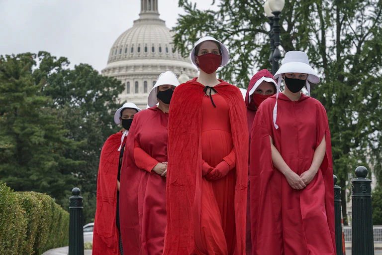 Women dresses in long red cloaks and red bonnets seen in front of Capitol Hill in Washington.