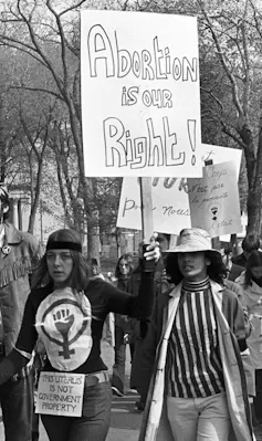 Women seen with signs saying 'abortion is our right' and 'my uterus is not government property.