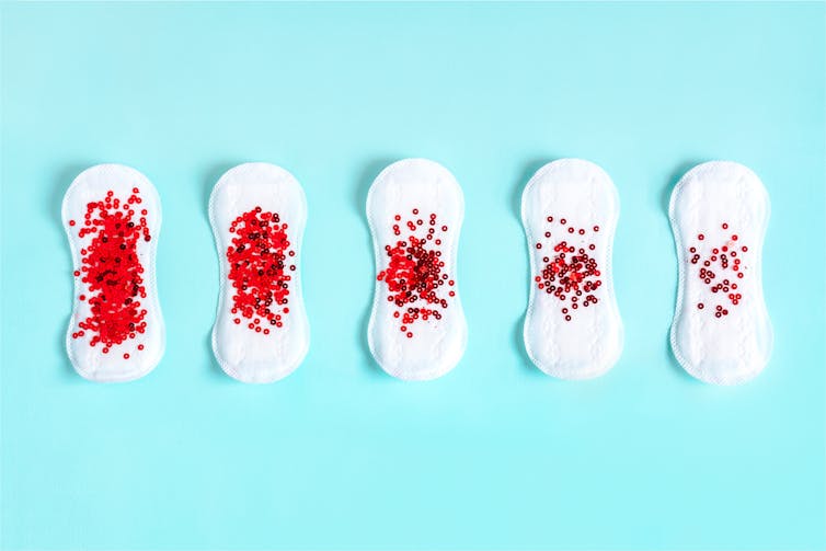 series of menstrual pads with red sequins to represent blood flow