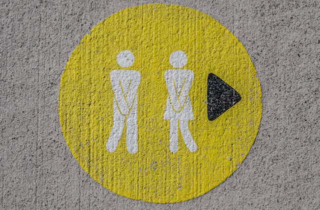 Toilet sign of man and woman holding hands over their groins