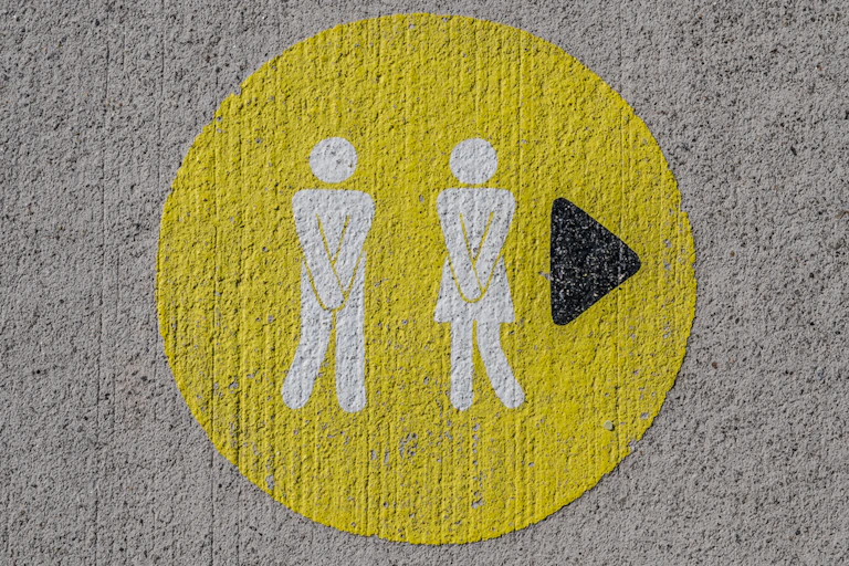 Toilet sign of man and woman holding hands over their groins