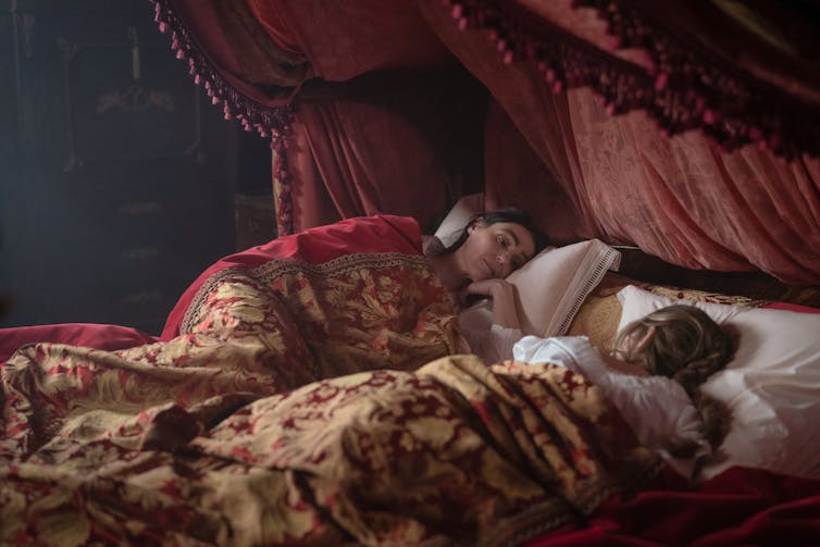 Two women in a lavishly draped bed.
