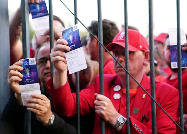 Football fans stuck outside a gate show tickets