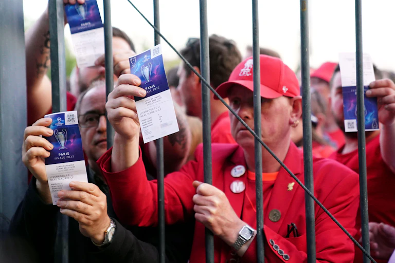 Football fans stuck outside a gate show tickets
