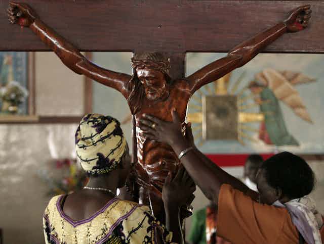 Catholics reach to touch a wood crucifix at the Catholic Basilica Church in Namugongo, Uganda