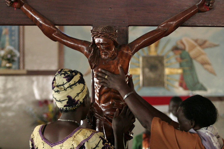 Catholics reach to touch a wood crucifix at the Catholic Basilica Church in Namugongo, Uganda
