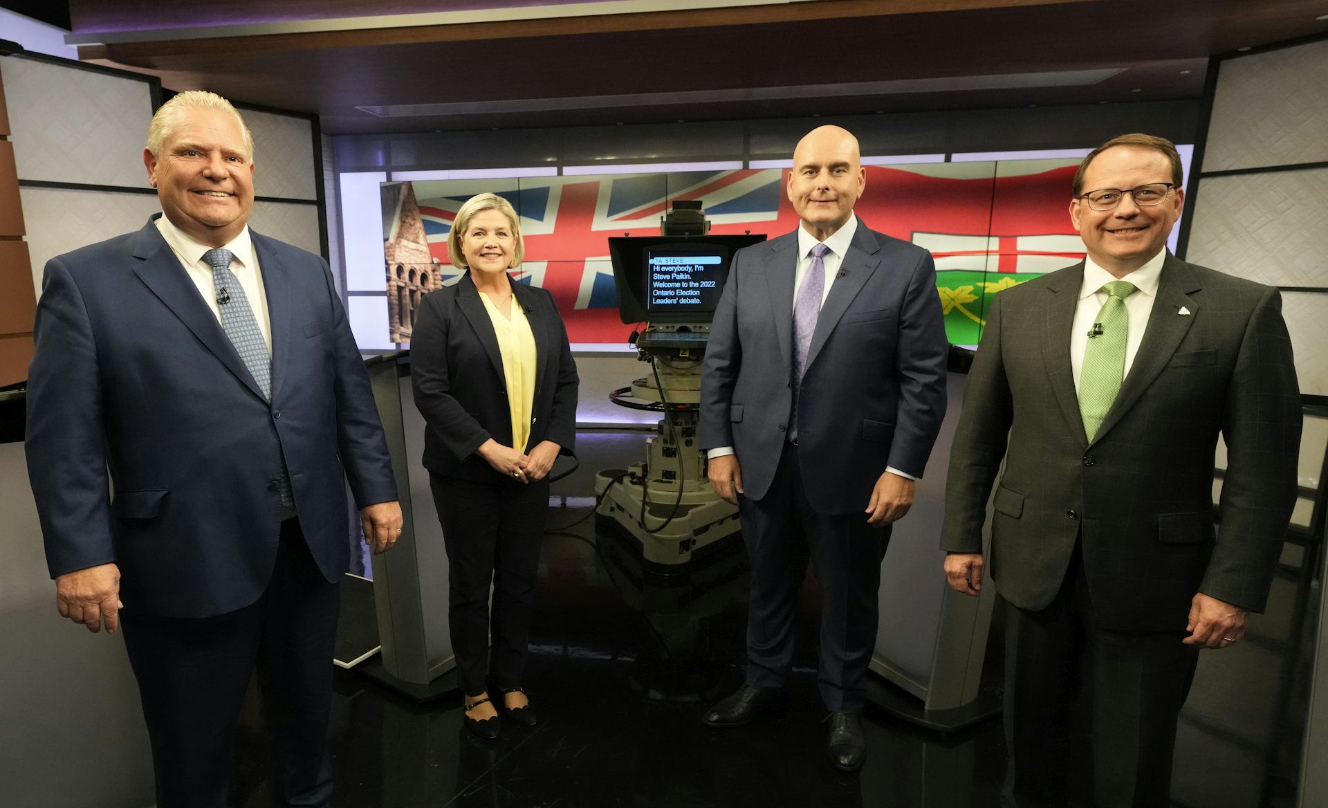 Three men and a woman stand in a line smiling at the camera.
