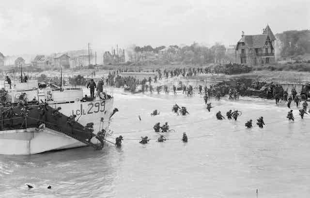 Soldiers walk through the water to shore