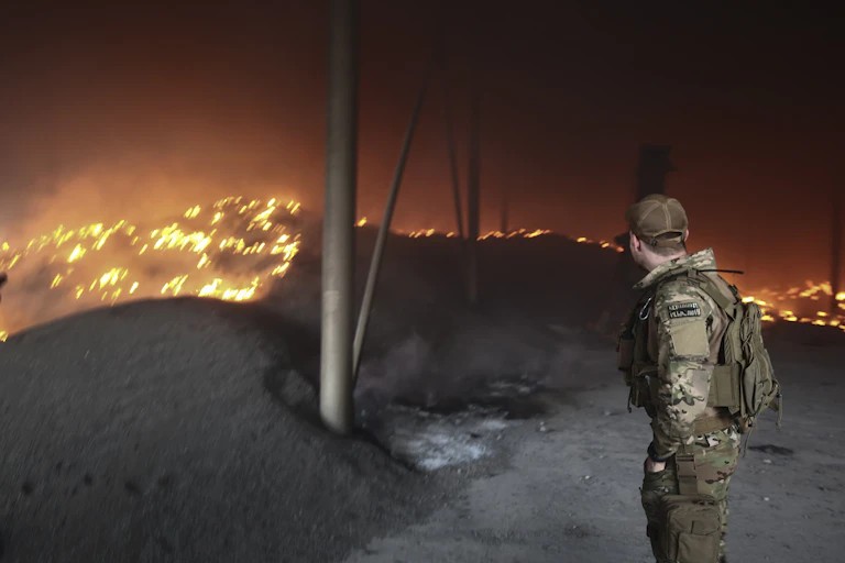 A Ukrainian soldier looks on at a sunflower seeds storage on fire after shelling on a farm close to the front line near the city of Bakhmut, Donetsk region,
