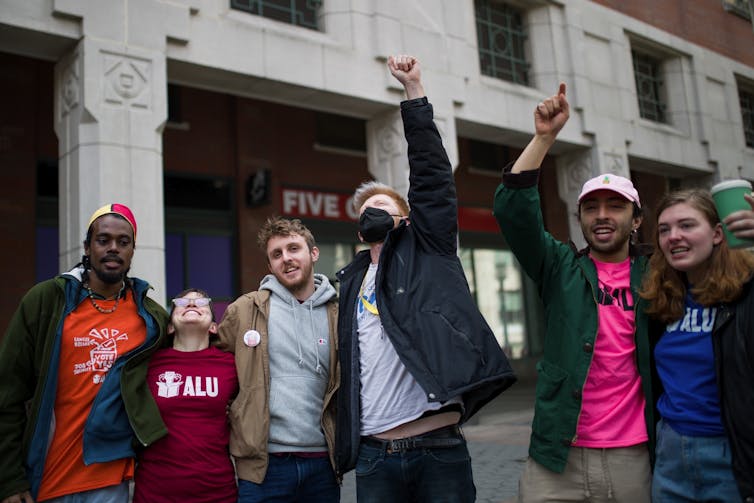 A group of people standing with their hands in the air and smiles on their faces