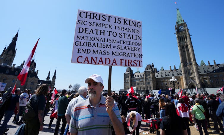 A man holding a protest sign in a crowd of people