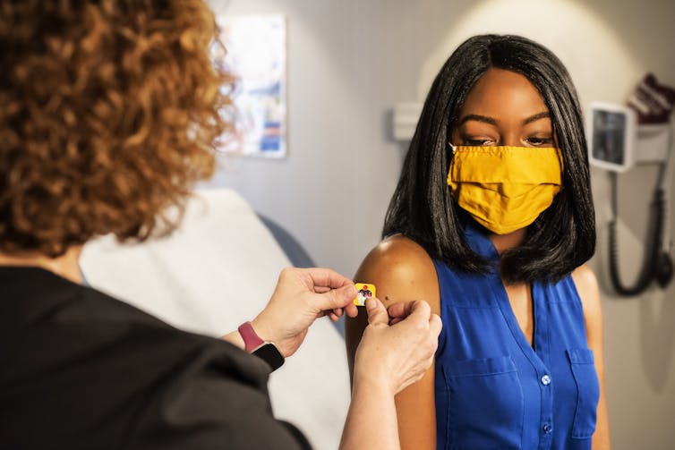 A nurse puts a bandaid on a woman's arm after an vaccination.