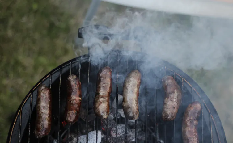 Sausages over a smoky grill.