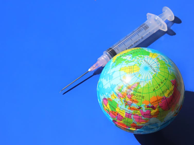 A globe and a syringe against a blue background
