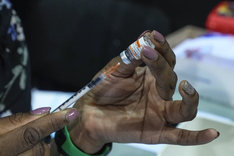 Hands holding a syringe and vial of vaccine