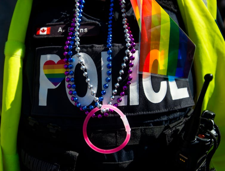 A close up of a police uniform with a red rainbow flag on it