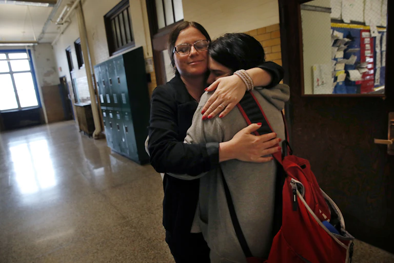 A woman hugs a young adult