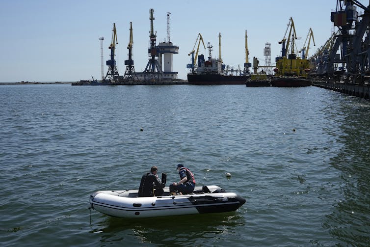 Men in a dinghy work in a port.