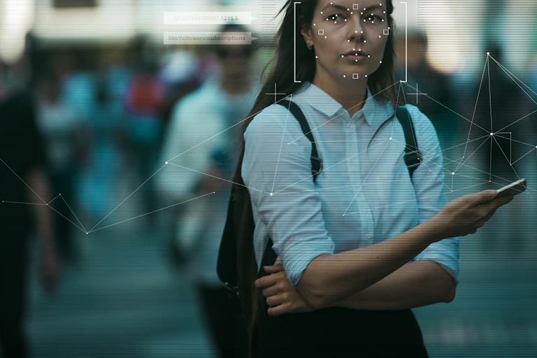 Woman with long dark hair holds smartphone and looks away from the frame
