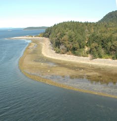 An aerial view of an island coastline with a rocky wall creating an intertidal pool area.