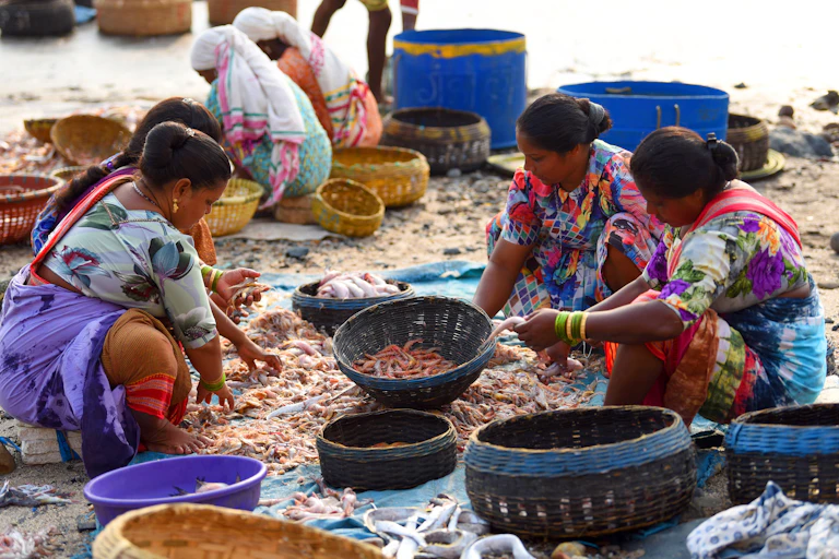 Three fisherwomen sit with the catch of the day