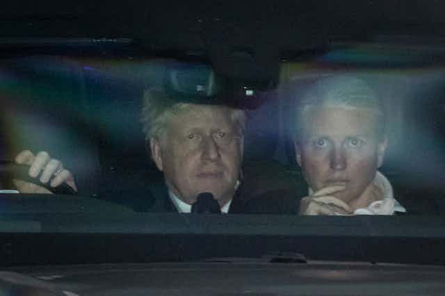 Boris Johnson sites in the back of a car with an aide after narrowly winning a no-confidence vote on June 6 2022.