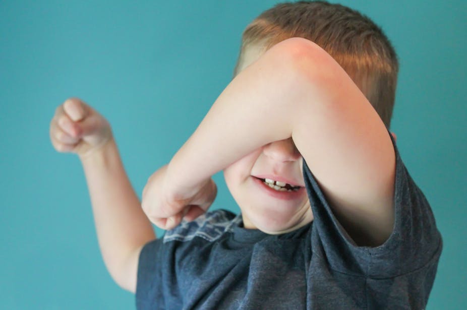 A young boy uses his arm to shield his face.
