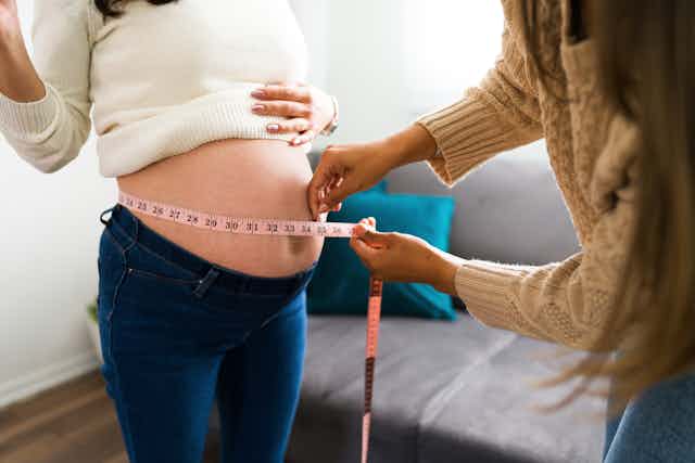 A pregnant person is having their stomach measured.