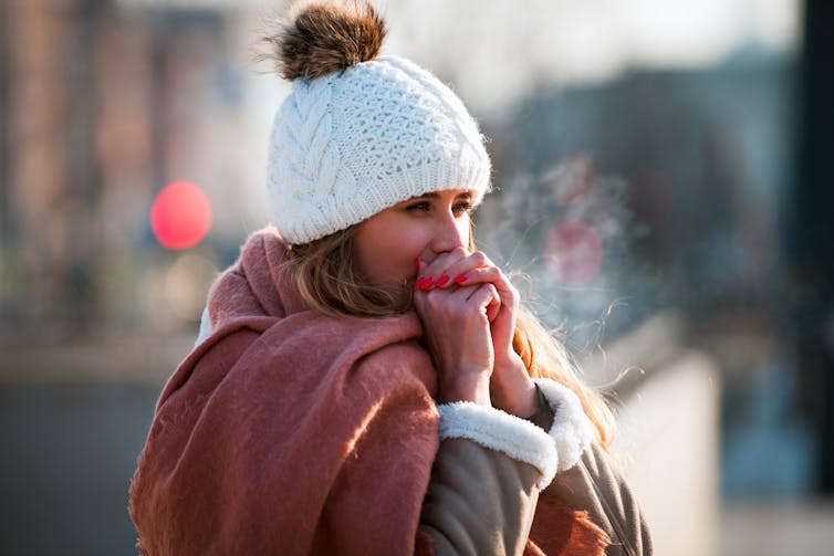 Woman in beanie warming her hands