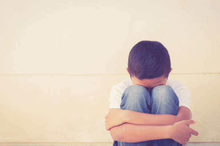 Boy folding his arms around his knees.