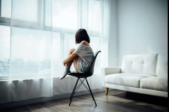 Woman sitting on chair looking out window
