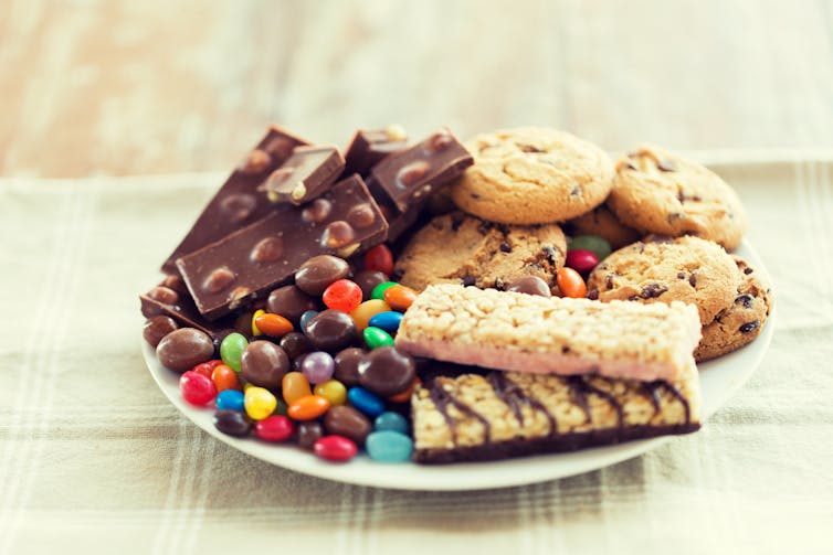A plate full of unhealthy, sugary foods – including chocolate bars, sweets and cookies.
