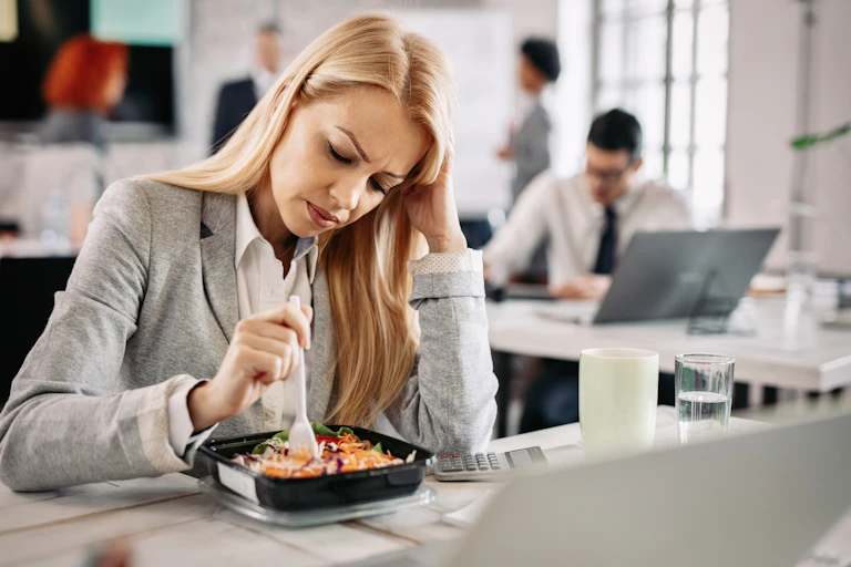 A young women in business clothes looks down at her lunch in disappointment.
