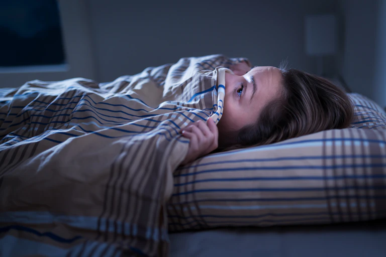Woman in bed looking scared