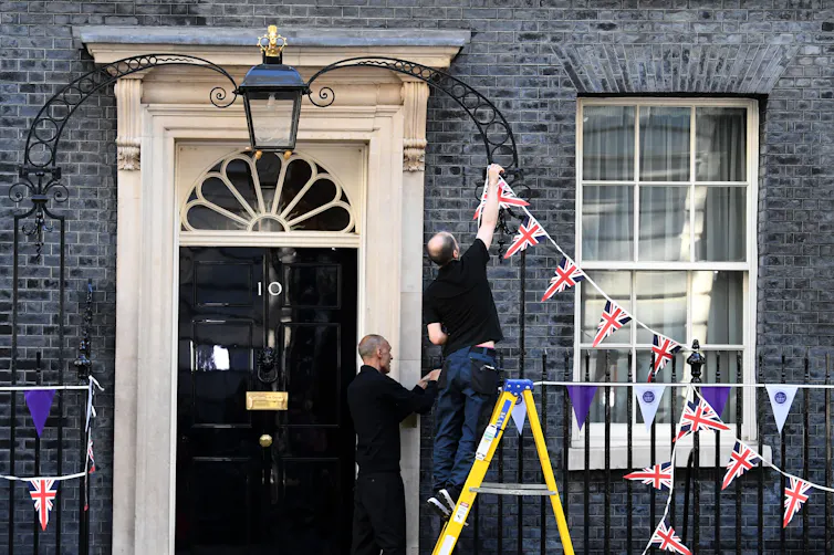 Workers removing Union Jack and Platinum Jubilee bunting from the fence outside of Number 10 Downing Street.