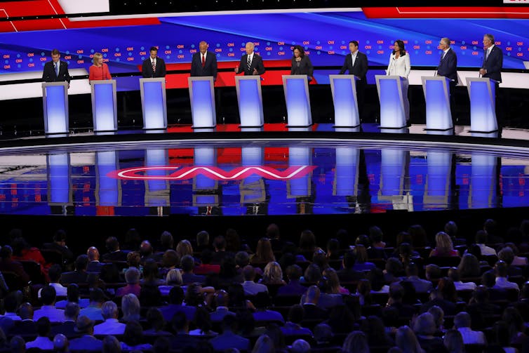 Ten people standing on stage behind illuminated lecterns.