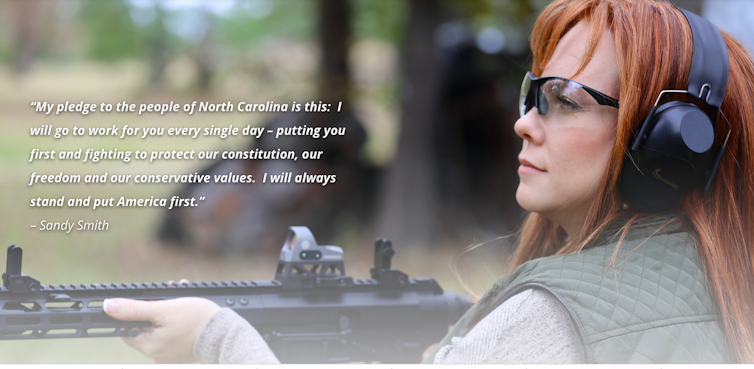 In a campaign website photo, a woman wearing goggles and ear protectors holds a gun.
