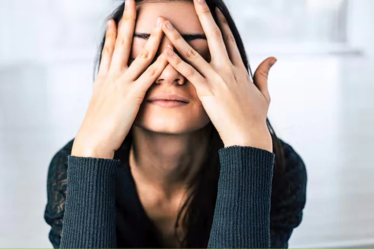 Gadis berambut gelap menutupi wajahnya dengan tangan