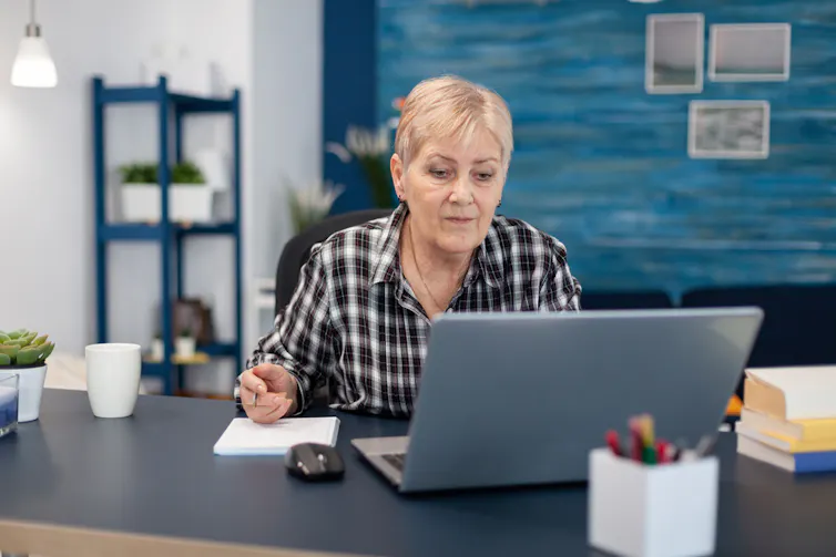 Une femme assise devant son ordinateur, prenant des notes