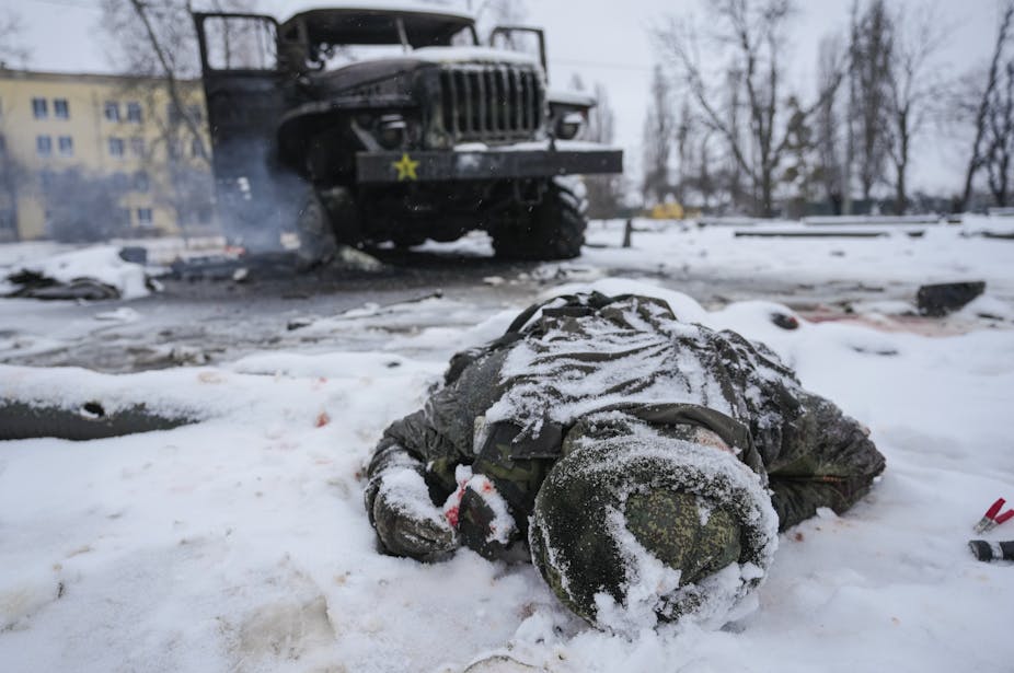 A body lies in the snow next to a truck