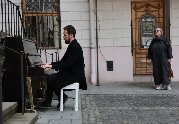 Un hombre toca un piano en la calle.