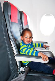 un niño emocionado se sienta en el asiento de la ventana de un avión