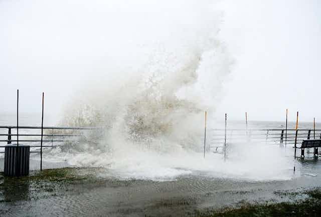 grande vague déferlant sur une promenade au bord de la mer