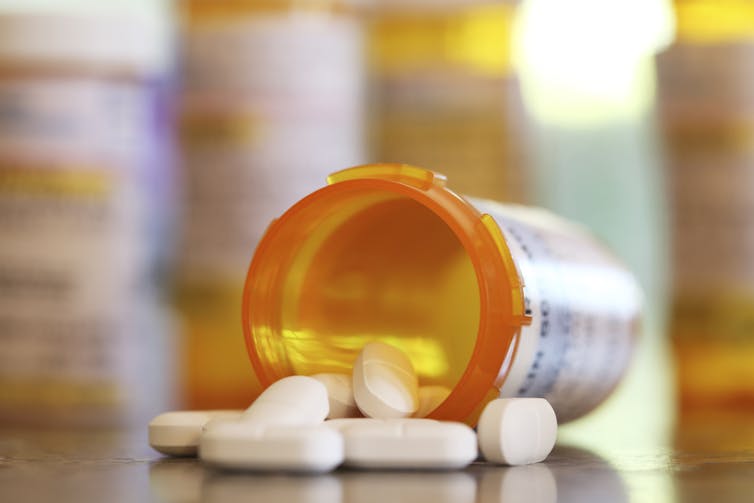 White pills spilling out of orange bottle