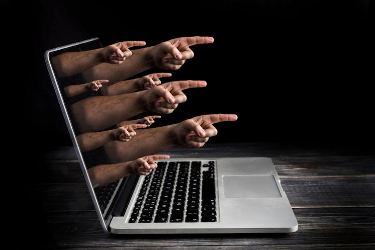 Multiple hands pointing a finger coming out of a laptop screen