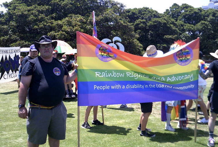 Group of people march with rainbow flag