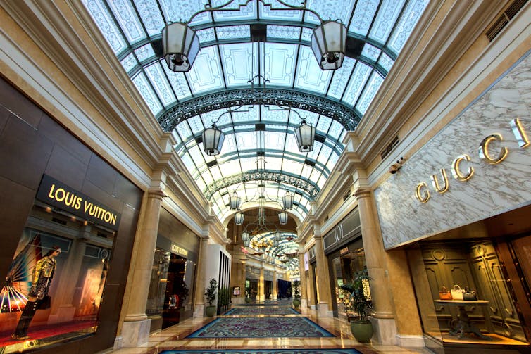 An indoor shopping arcade is lined with luxury stores on either side