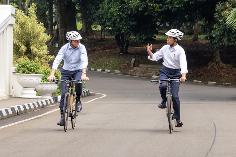 Two men chat as they ride side by side on bicycles