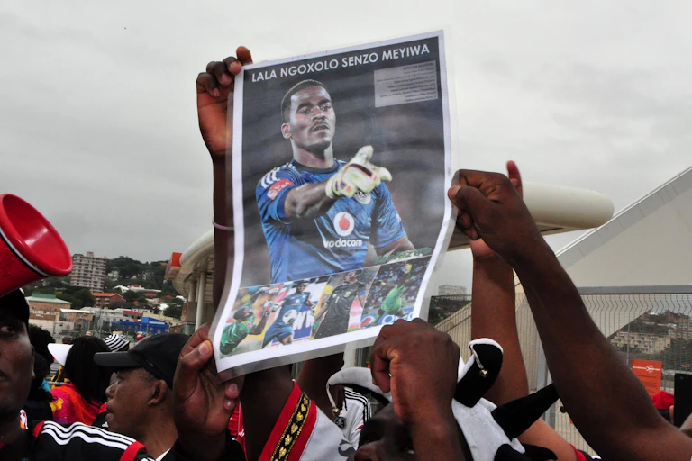 Hands hold up a poster of a man in football gear pointing with a gloved hand